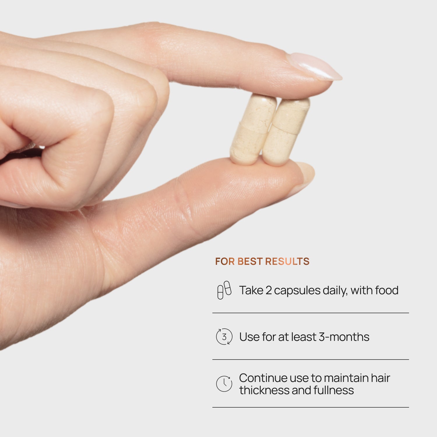 Hand holding two capsules with hair care instructions on a light gray background